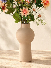Detail vaas Apricot Garden zijden boeket met abrikooskleurige, oranje, lila en blauwe bloemen in een matte zandkleurige vaas.
