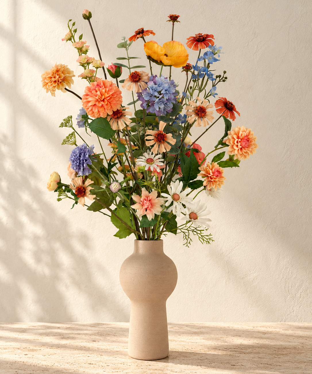 Apricot Garden zijden boeket met abrikooskleurige, oranje, lila en blauwe bloemen in een matte zandkleurige vaas.