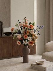 Blush Garden zijden boeket in keramische vaas met crème, blush en blauwe bloemen op salontafel