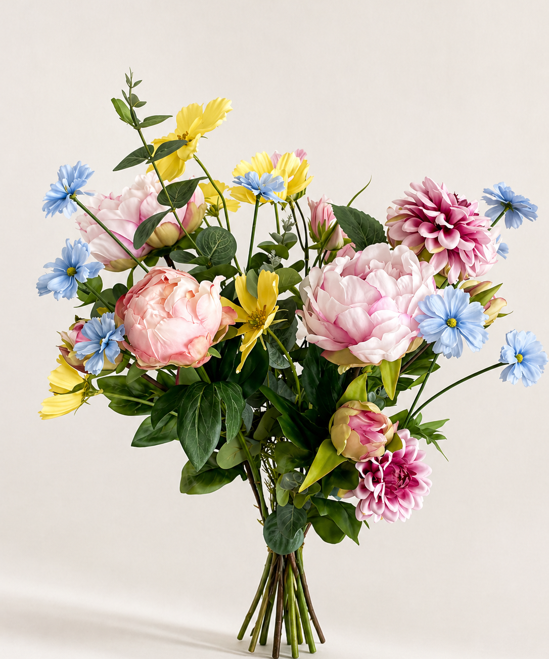 Zijden boeket met pioenrozen en bloemen in pastel geel, blauw en roze op lichte achtergrond
