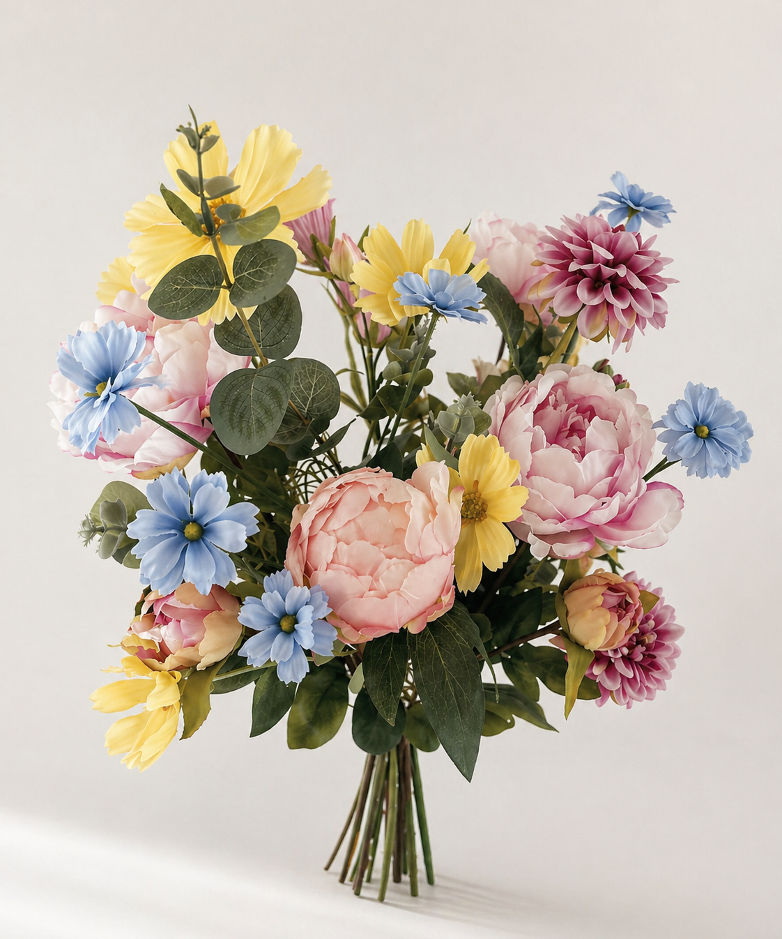 Zijden boeket met pioenrozen en bloemen in pastel geel, blauw en roze op lichte achtergrond
