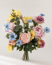 Zijden boeket met pioenrozen en bloemen in pastel geel, blauw en roze op lichte achtergrond
