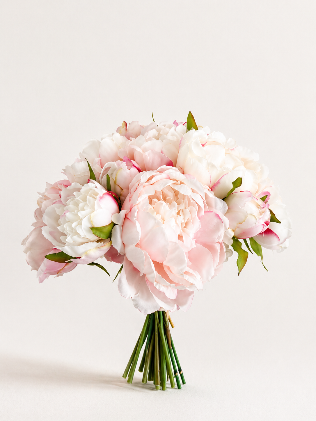 Zijden pioenrozen boeket in zacht roze en wit met volle bloemen op lichte achtergrond
