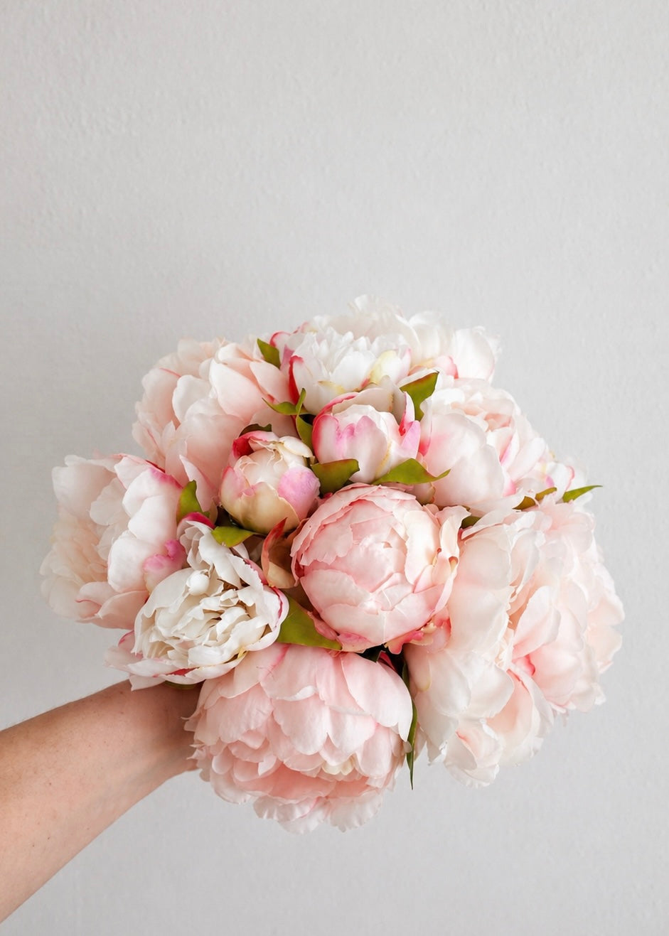 Zijden pioenrozen boeket in zacht roze en wit met volle bloemen op lichte achtergrond